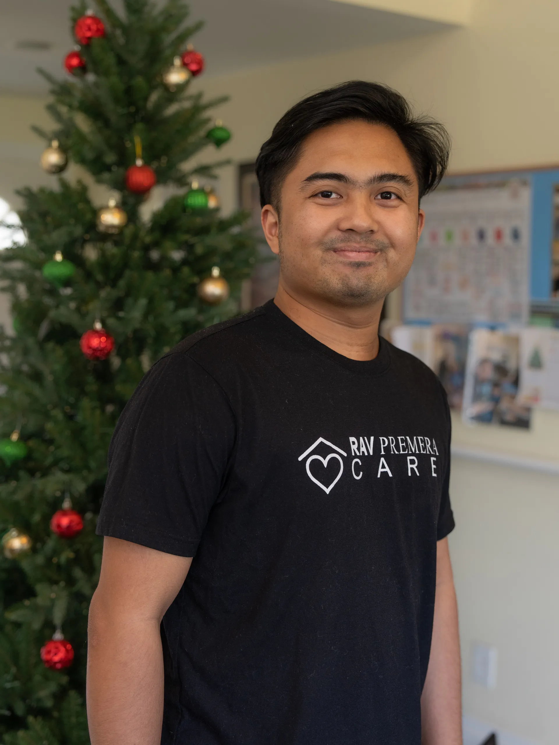 Caregiver wearing RAV Premier Care shirt standing in facility during holiday season